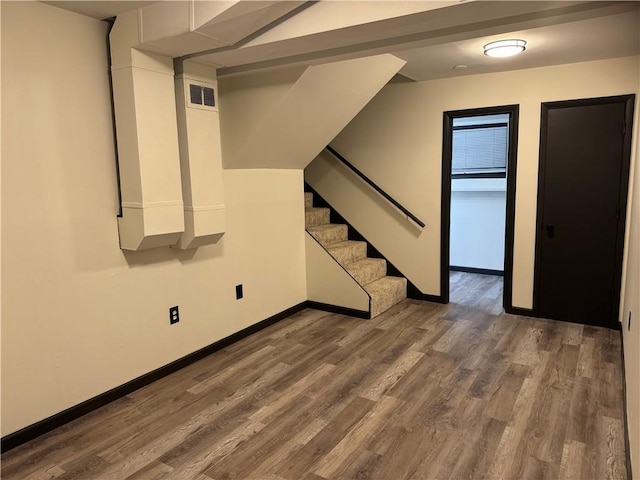 basement with visible vents, stairs, baseboards, and wood finished floors