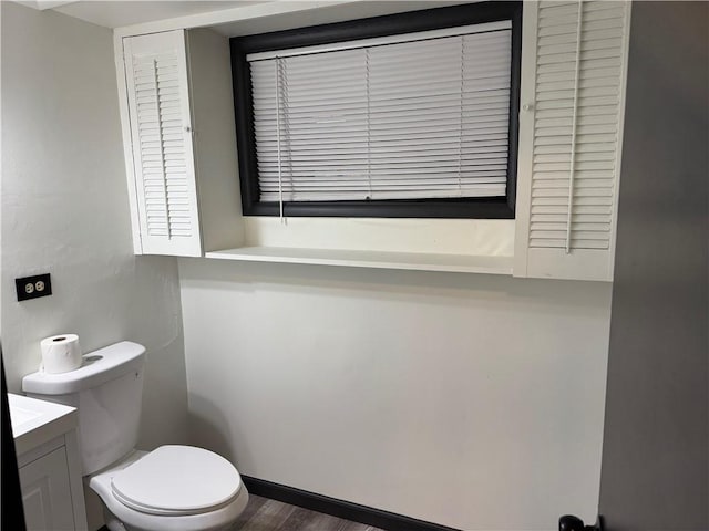 half bath featuring toilet, wood finished floors, and vanity