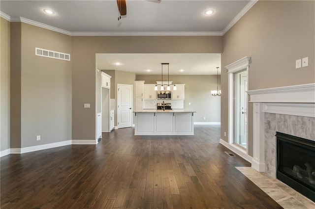 unfurnished living room featuring dark wood-style floors, visible vents, baseboards, a high end fireplace, and crown molding