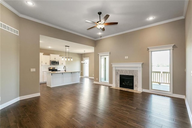 unfurnished living room with baseboards, dark wood-type flooring, a ceiling fan, and crown molding