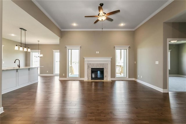 unfurnished living room with a ceiling fan, dark wood-style floors, baseboards, a fireplace, and ornamental molding