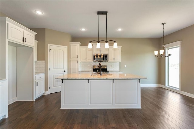 kitchen with a sink, light stone counters, appliances with stainless steel finishes, white cabinetry, and dark wood-style flooring