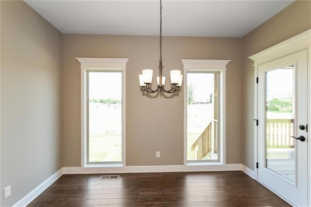 unfurnished dining area featuring a wealth of natural light, visible vents, a notable chandelier, and dark wood-style flooring