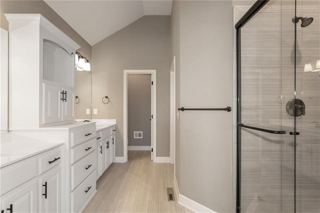 full bath with vanity, a shower stall, and vaulted ceiling