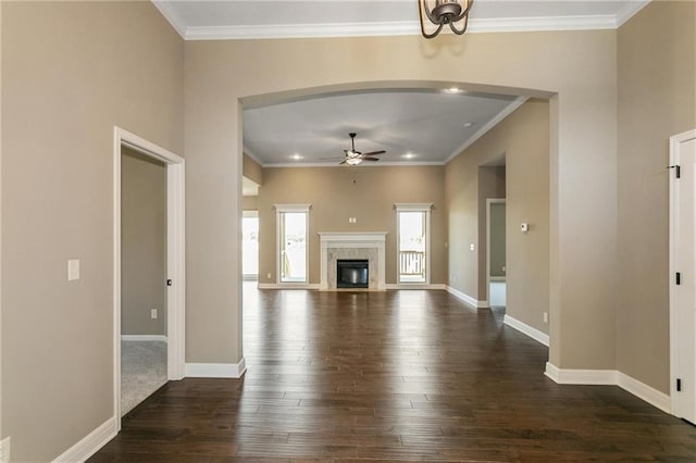 unfurnished living room with baseboards, ornamental molding, a fireplace, a ceiling fan, and dark wood-style flooring