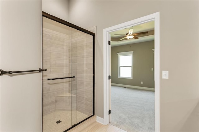 bathroom with ceiling fan, a stall shower, and baseboards