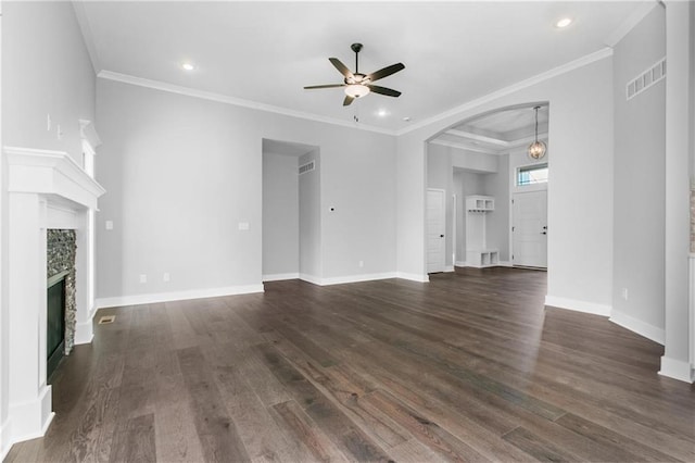 unfurnished living room with visible vents, dark wood-type flooring, ornamental molding, a glass covered fireplace, and baseboards