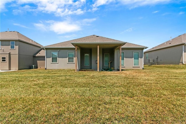 back of property with central AC unit and a yard