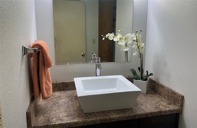 bathroom with a textured wall and vanity