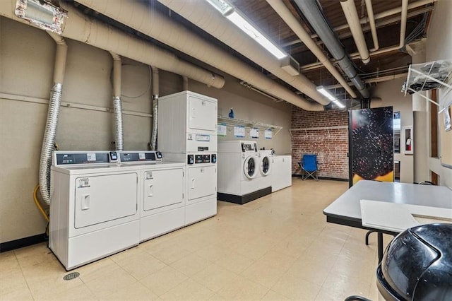 community laundry room with stacked washer and clothes dryer, separate washer and dryer, light floors, and brick wall