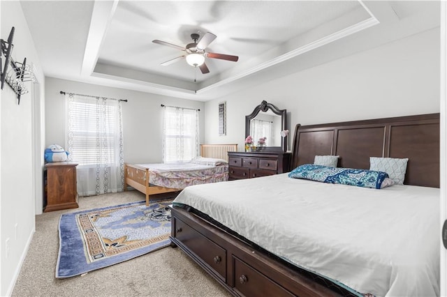 bedroom with light colored carpet, baseboards, a tray ceiling, and a ceiling fan