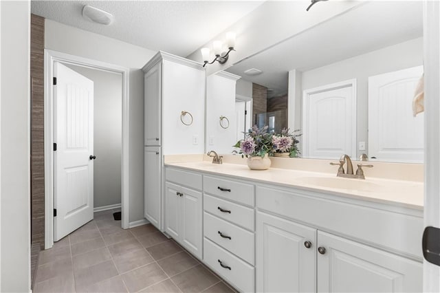 bathroom with a sink, a textured ceiling, double vanity, and tile patterned floors