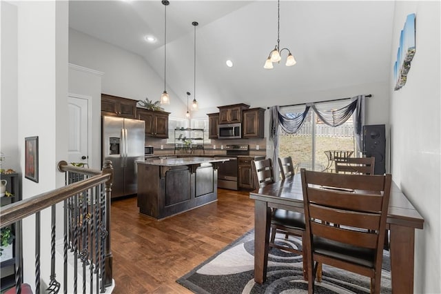 kitchen featuring dark brown cabinets, a kitchen island, dark wood-type flooring, a breakfast bar, and appliances with stainless steel finishes