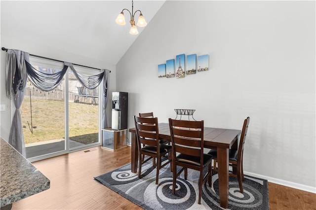 dining room with baseboards, high vaulted ceiling, an inviting chandelier, and wood finished floors