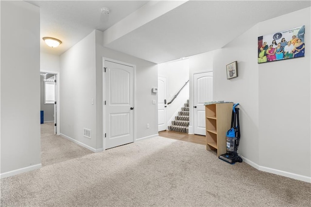 below grade area with visible vents, carpet floors, baseboards, and stairway