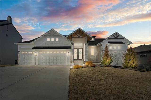 view of front of home featuring a lawn, a standing seam roof, french doors, concrete driveway, and a garage