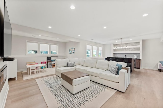 living room featuring indoor wet bar, light wood-style flooring, recessed lighting, and baseboards