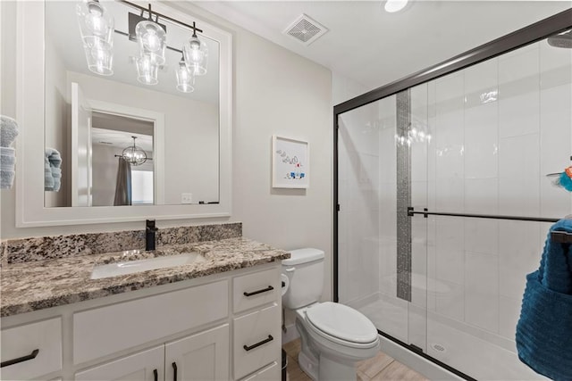 full bathroom featuring vanity, a shower stall, toilet, and visible vents