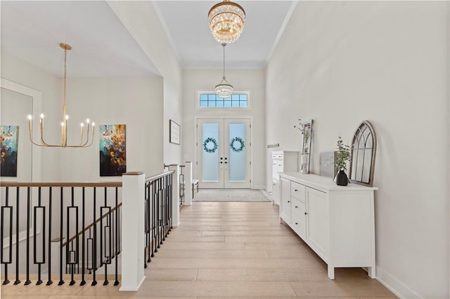 foyer entrance featuring a chandelier, french doors, light wood-style floors, and ornamental molding