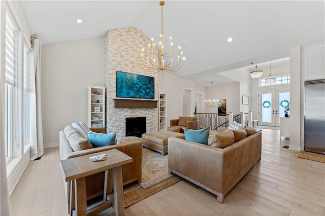 living room with light wood-type flooring, high vaulted ceiling, a chandelier, and a fireplace