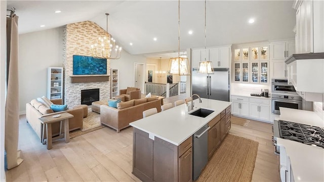 kitchen with a center island with sink, light countertops, light wood-style flooring, stainless steel appliances, and a sink