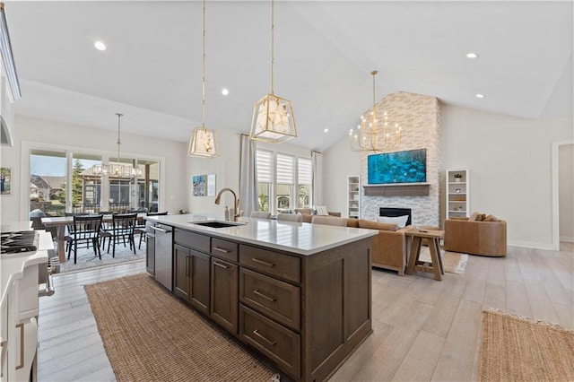 kitchen with a fireplace, a sink, dark brown cabinets, stainless steel dishwasher, and a notable chandelier