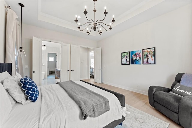 bedroom with an inviting chandelier, baseboards, light wood-style floors, and a tray ceiling