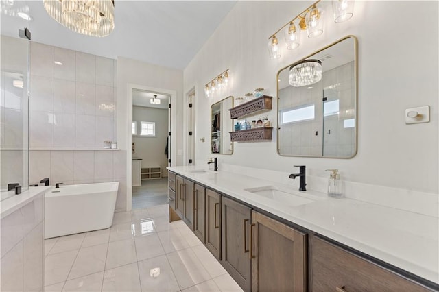 full bath featuring a sink, tile walls, a tile shower, and a chandelier