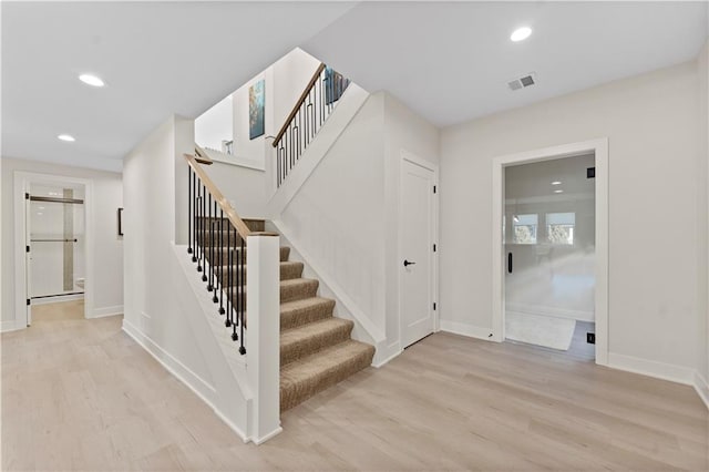 stairs with recessed lighting, wood finished floors, visible vents, and baseboards