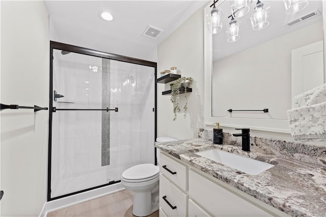 bathroom with visible vents, vanity, toilet, and a shower stall