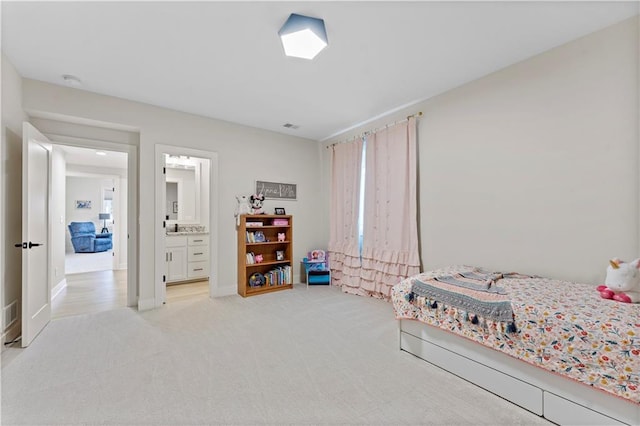 bedroom with ensuite bath, baseboards, and light carpet