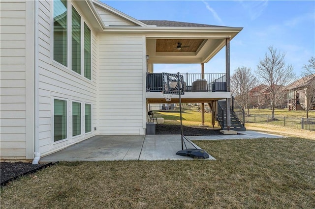 exterior space with ceiling fan, fence, stairs, a lawn, and a patio