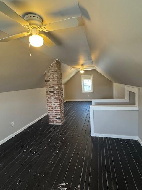 additional living space featuring lofted ceiling, a ceiling fan, baseboards, dark wood-style flooring, and ornate columns