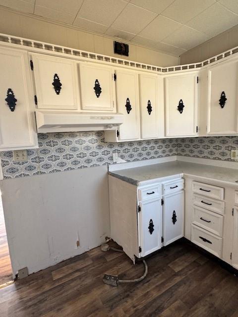 kitchen with under cabinet range hood, dark wood finished floors, light countertops, vaulted ceiling, and white cabinetry