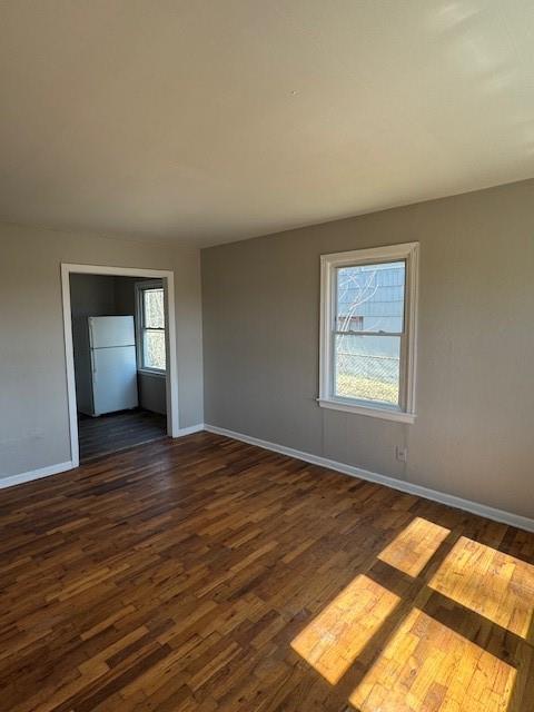 unfurnished room with dark wood-style floors and baseboards