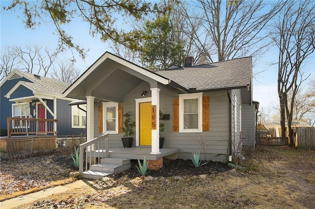 bungalow with fence, roof with shingles, and a chimney