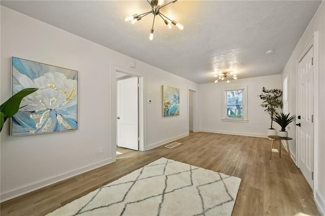 foyer featuring a chandelier, visible vents, baseboards, and wood finished floors