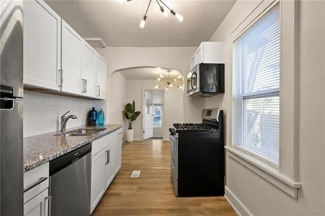 kitchen with a notable chandelier, a sink, tasteful backsplash, stainless steel appliances, and arched walkways