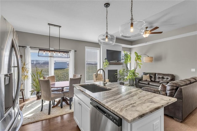 kitchen with a sink, stainless steel appliances, a kitchen island with sink, and open floor plan