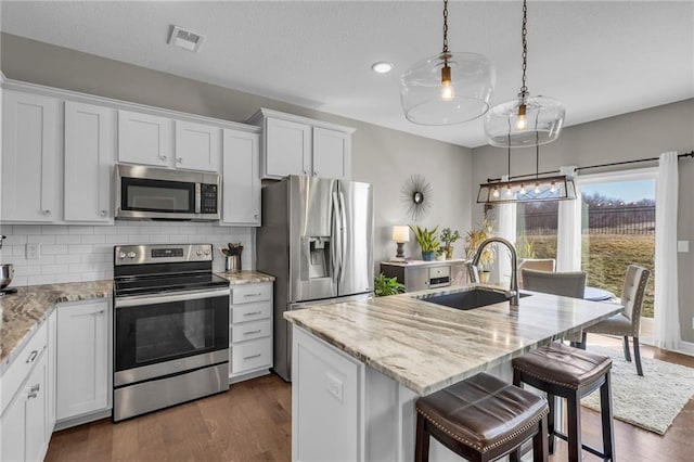 kitchen featuring visible vents, backsplash, appliances with stainless steel finishes, and a sink