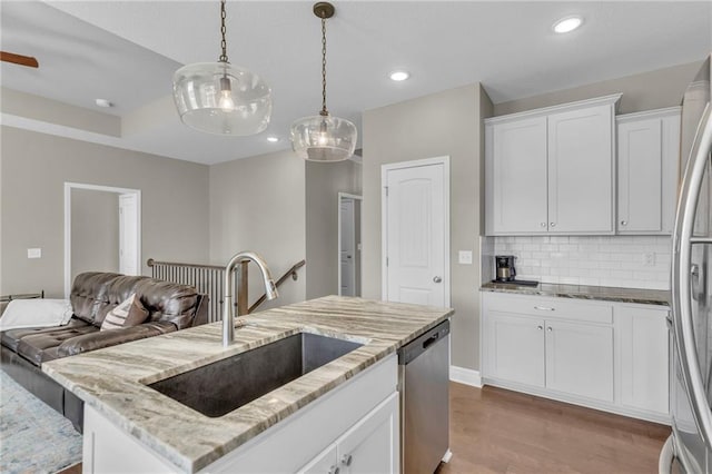 kitchen featuring decorative light fixtures, decorative backsplash, wood finished floors, stainless steel appliances, and a sink