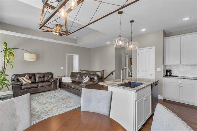 kitchen featuring a sink, decorative backsplash, stainless steel dishwasher, and open floor plan