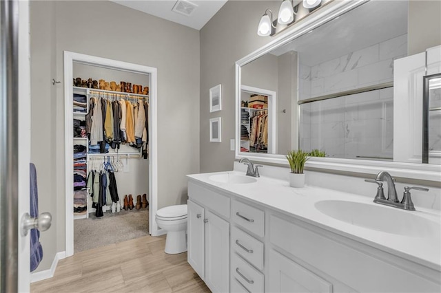 bathroom featuring double vanity, visible vents, a shower stall, and a sink