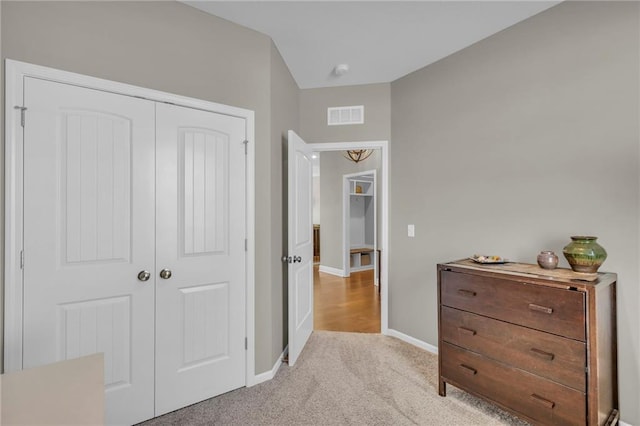 bedroom with light carpet, visible vents, baseboards, and a closet