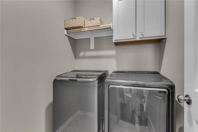 clothes washing area featuring cabinet space and washer and dryer