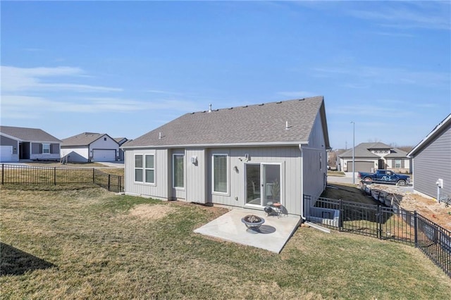 back of house featuring a patio, roof with shingles, a yard, a fenced backyard, and a fire pit