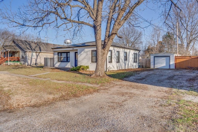 ranch-style home featuring fence, a front yard, a garage, an outbuilding, and driveway