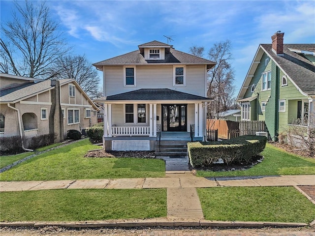 traditional style home featuring covered porch, a shingled roof, a front lawn, and fence