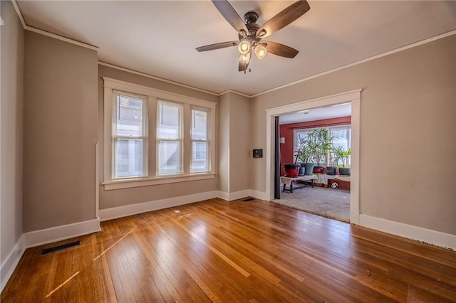 spare room with visible vents, crown molding, and hardwood / wood-style floors