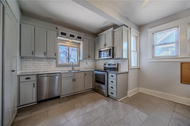 kitchen featuring tasteful backsplash, stainless steel appliances, baseboards, and a sink